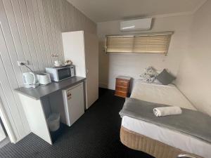 een kleine slaapkamer met een bed en een magnetron bij Dalby Hotel Motel in Dalby