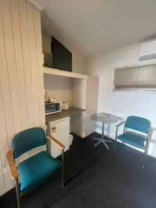 Zimmer mit 2 Stühlen, einem Tisch und einer Küche in der Unterkunft Dalby Hotel Motel in Dalby