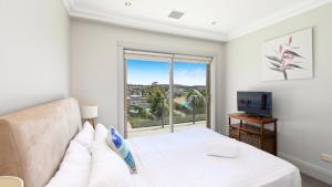 Un dormitorio con una cama y un televisor y una ventana. en Unit 48 - 3 Bed Ocean View, en Terrigal