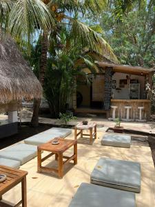 a patio with benches and tables in front of a house at Nelly homestay in Gili Islands