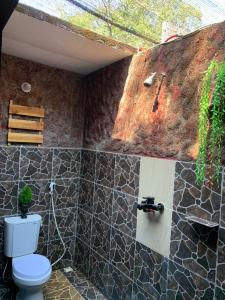 a bathroom with a toilet and a rock wall at Nelly homestay in Gili Islands