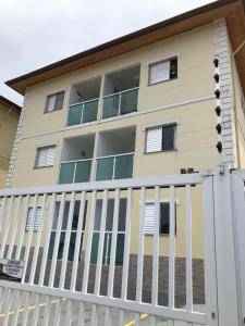 ein Gebäude mit einem weißen Zaun davor in der Unterkunft Apartamento completo Condomínio Caribe Ubatuba in Ubatuba