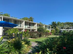 an apartment building with a garden and an umbrella at Beachfront Terraces with Onsite Reception & Check In in Port Douglas