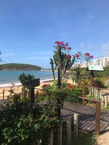 a boardwalk leading to the beach with flowers on it at Apartamento peracanga com vista para o mar in Guarapari