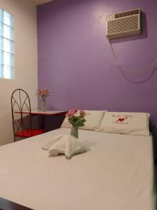 ein Schlafzimmer mit einem weißen Bett mit einer Blumenvase darauf in der Unterkunft WJV INN Canduman in Mandaue City