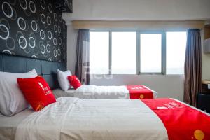 two beds in a hotel room with red and white pillows at RedLiving Apartemen Star Semarang - Sky Tower Lantai 22 in Semarang