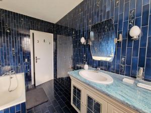 Baño de azulejos azules con lavabo y espejo en Holiday home in Perros Guirec, en Perros-Guirec