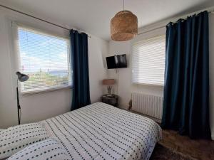 a bedroom with a bed and two windows with blue curtains at Holiday home in Perros Guirec in Perros-Guirec