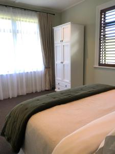 sypialnia z łóżkiem i oknem z zasłonami w obiekcie River View Cottage w mieście Kahuranaki