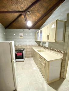 a kitchen with wooden cabinets and a refrigerator at شقق السودة هاوس in Suda