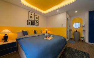 um quarto com uma grande cama azul e paredes amarelas em Pavillon Garden Hotel & Spa Nha Trang em Nha Trang