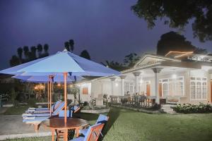 a table and chairs with an umbrella in front of a house at RedDoorz near Taman Safari 2 in Bogor