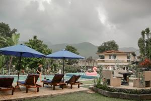 a person standing near a pool with chairs and umbrellas at RedDoorz near Taman Safari 2 in Bogor