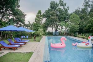 a swimming pool with pink flamingos and chairs at RedDoorz near Taman Safari 2 in Bogor