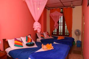 a room with three beds with colorful pillows at Little Heaven in Ella