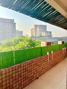 a brick wall with a green fence in a city at House Of Comfort Delhi in New Delhi