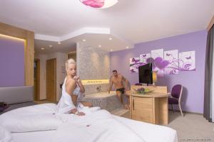 a woman sitting on a bed with a man in a bathroom at ... mein romantisches Hotel Toalstock in Fiss