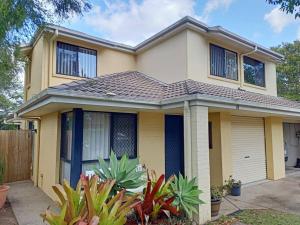 uma casa amarela com uma cerca em frente em Tingalpa Townhouse Treat em Brisbane