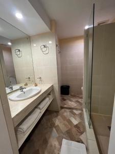 ein Bad mit einem Waschbecken und einer Dusche in der Unterkunft Coco Grande Hotel in Dumaguete