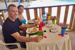 un hombre y una mujer sentados en una mesa comiendo comida en Private Cabin in San Blas, en Waisalatupo