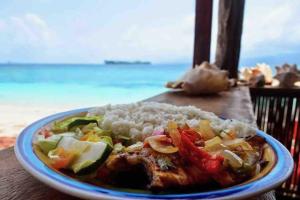 a plate of food with rice and vegetables on a table at Private Cabin in San Blas in Waisalatupo