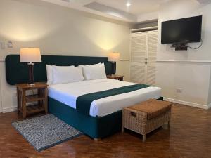 Coco Grande Hotel في دوماغيتي: غرفة نوم مع سرير كبير وتلفزيون على الحائط
