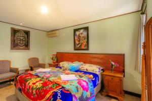 1 dormitorio con 1 cama con un edredón colorido en Pacung Indah Hotel & Restaurant by ecommerceloka en Bedugul