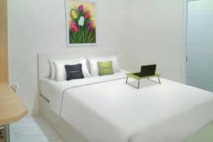 a white bed with a chair and a painting on the wall at Urbanview Syariah Utami Inn Garut by RedDoorz in Garut