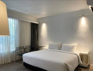 a bedroom with a large white bed and a window at POR Santitham in Chiang Mai