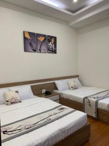 2 camas en una habitación con paredes blancas en Khách sạn Khang An Buôn Ma Thuột, en Buon Ma Thuot
