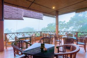 um restaurante com mesas e cadeiras numa varanda em Pacung Indah Hotel & Restaurant by ecommerceloka em Bedugul