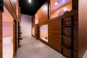 Cette chambre est dotée de murs en bois et d'un couloir avec des lits superposés. dans l'établissement Jpod Capsule Hotel, à Kota Kinabalu