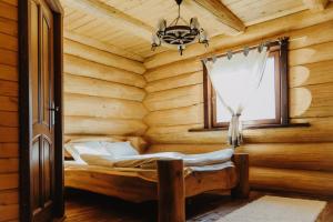 a bedroom in a log cabin with a bed and a window at Prosilva house in Topliţa +15 photos