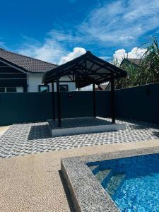 a pavilion next to a swimming pool next to a house at Villa Pool Kepala Batas in Kampong Hilir