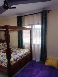 a bedroom with a bed and a window with curtains at Coasterian Apartment in Mombasa