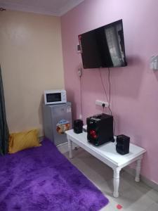 a room with a small refrigerator and a tv on the wall at Coasterian Apartment in Mombasa