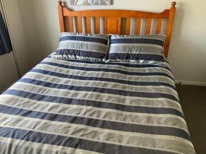 a bed with blue and white striped sheets and pillows at Large stand alone home with two living areas. in Taupo