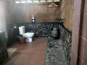 a bathroom with a toilet and a stone wall at Gili Hideaway in Gili Trawangan