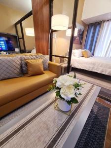 a living room with a couch and a table with flowers at Staycation by Ness in Ayala Makati in Manila