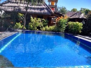 a blue swimming pool in front of a house at Gili Hideaway in Gili Trawangan