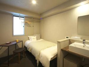 um quarto de hotel com uma cama e um lavatório em Hotel Gee Haive em Mishima