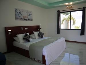 a bedroom with a bed with pillows and a window at Clouds Beach Retreat Laamu Gan in Gan