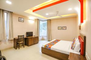 um quarto com uma cama, uma secretária e uma televisão em FabHotel Pine Tree em Noida