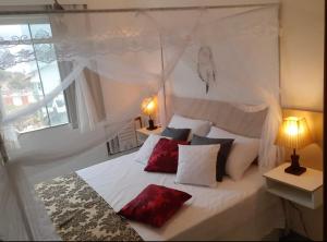 a bedroom with a white bed with red pillows at Flat Bela Vista in Macaé