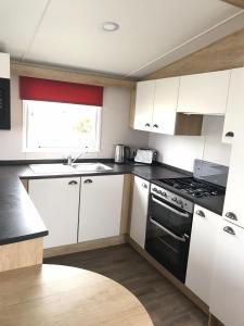 a kitchen with white cabinets and a black stove top oven at Haven Haggerston castle caravan hire in Cheswick