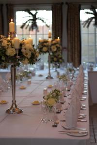 Una larga mesa blanca con velas y flores. en Dunsley Hall Hotel en Stourbridge