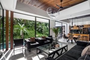 een open woonkamer met zwarte meubels en grote ramen bij Villa Three Little Birds by BaliSuperHost in Ubud