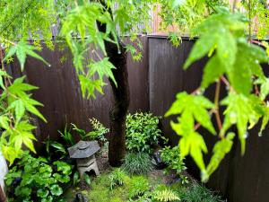einen Garten mit einer Steinbank neben einem Zaun in der Unterkunft Guesthouse Kioto in Kyoto