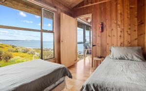 um quarto com 2 camas e uma grande janela em Cliffs End Beach Shack 105 Gold Coast Drive em Carrickalinga