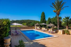 una piscina con sedie e ombrelloni in un cortile di Villa Cas Cuni a Felanitx